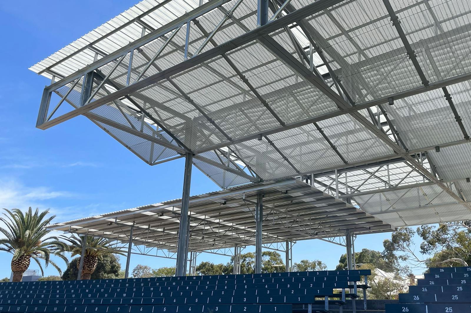 A photo of a sports pavilion with seating below, and blue sky behind.