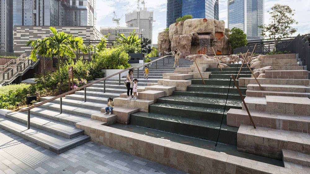 A photograph of a staircase in a rooftop park, beside a stepped water feature.