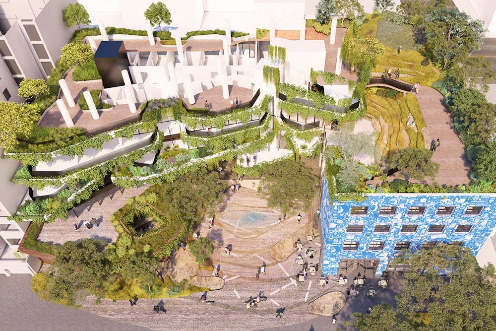 A digital render of an elevated view of a new building forecourt. There are trees, rooftop gardens, green walls, as well as a feature blue building facade in the bottom right corner.