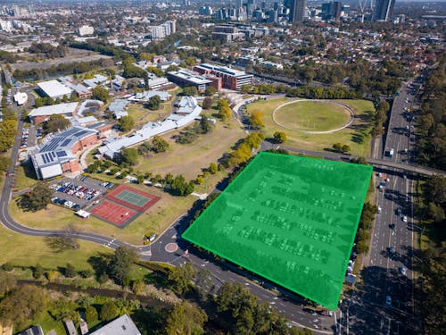 An aerial photograph of a university campus, a carpark in the foreground is highlighted with a green square to indicate the competition site. 