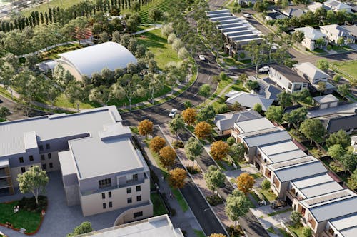 A digital render of a new residential community from above. There is an apartment building, townhouses, open space, and lots of trees.