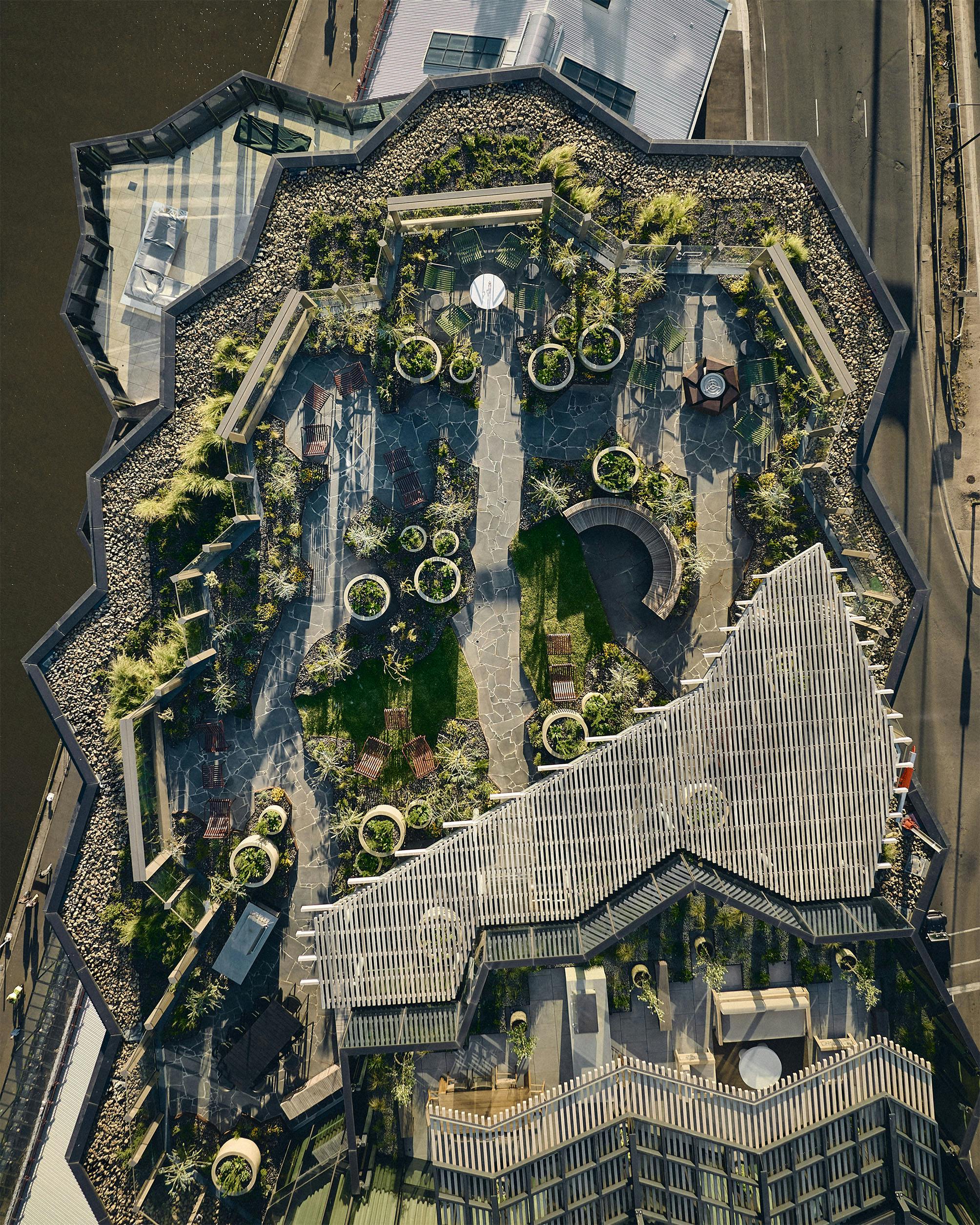 An aerial photograph of an intricate and geometric rooftop garden, with long shadows.
