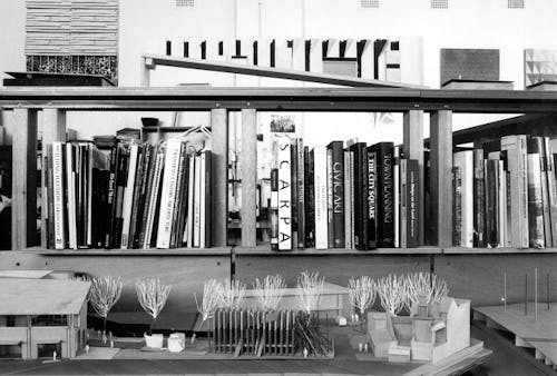 A black and white photograph of a bookshelf of landscape architecture books and models.