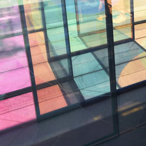 A photograph of sunlight refracted through coloured glass panels onto stone paving.