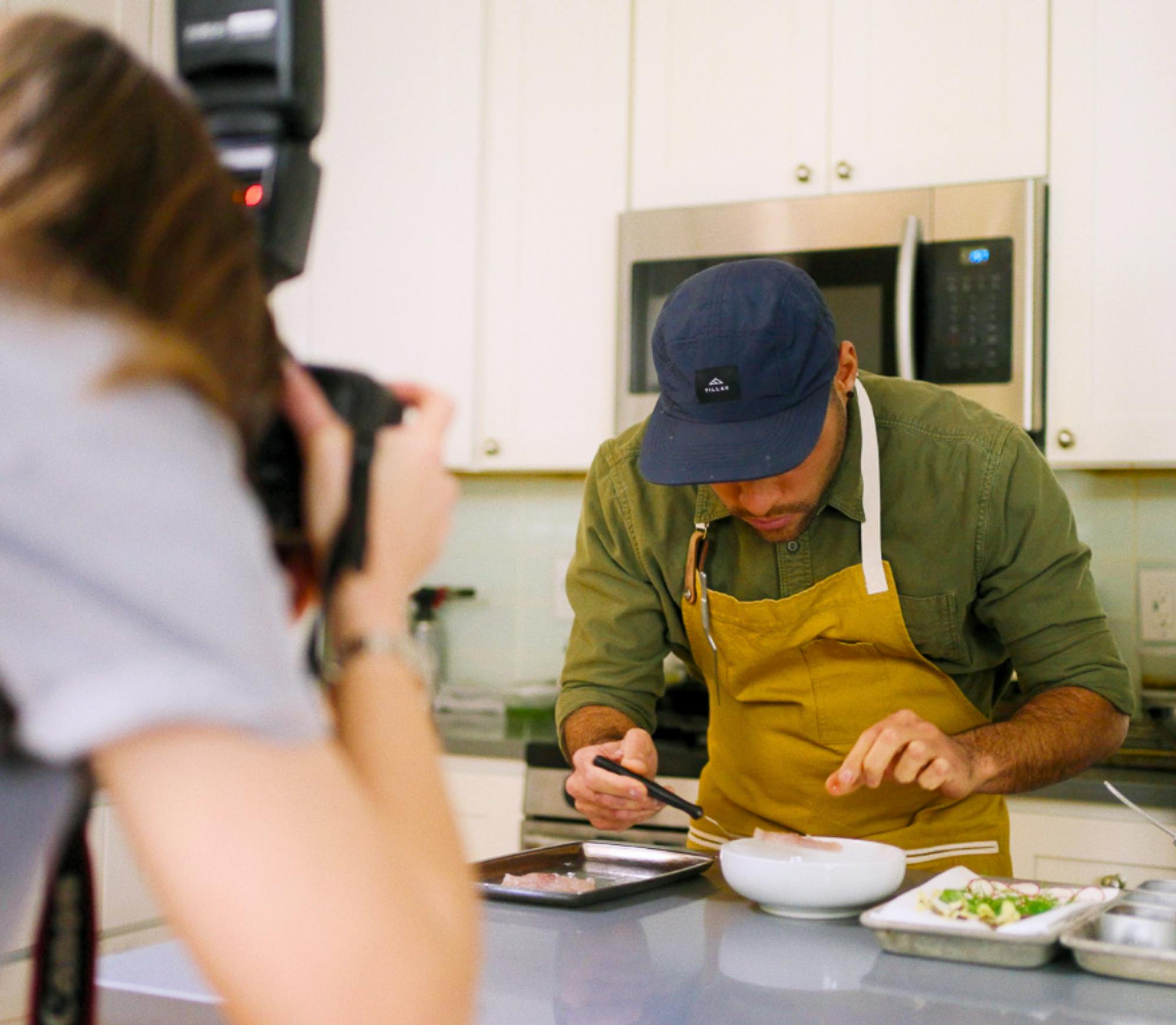 chef plating food and photographer taking photo