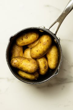 Pot full of whole potatoes in water.