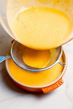orange mixture strained trough sieve on a dish