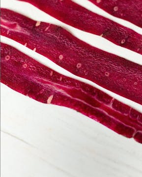 3 strands of beetroot spaghetti laid flat on a countertop.