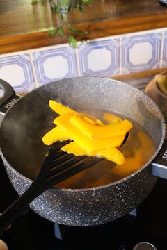 sliced butternut squash getting poured into boiling water 