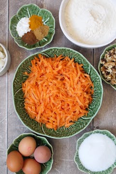 grated carrots in a bowl and other ingredients on their own bowl