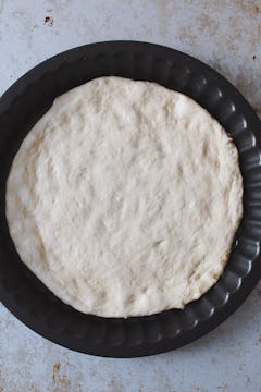 The ball of dough flattened to form a pizza base. 