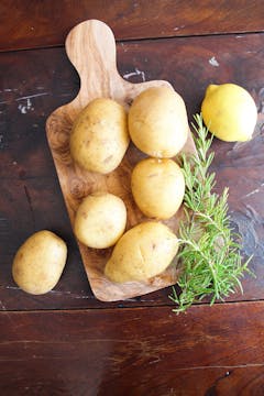 7 whole potatoes and springs on rosemary on a chopping board