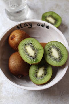 A bowl of kiwis. 3 kiwi halves are up facing the camera. 