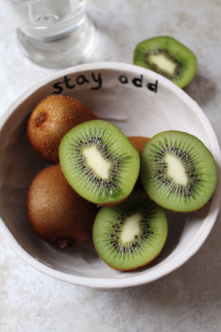 A bowl of kiwis. 3 kiwi halves are up facing the camera.