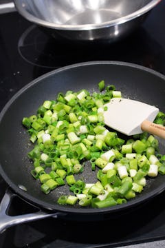 Spring onions being fried in a pan. 