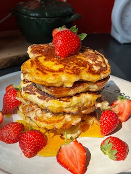 vegan pancakes topped with strawberries and maple syrup 