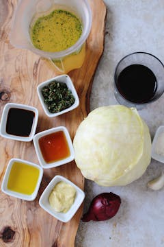 The ingredients required to marinate this head of cabbage. Thyme, maple syrup, mustard, soy sauce, and vegetable stock. 