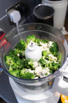broccoli heads in a food processor with seasoning 