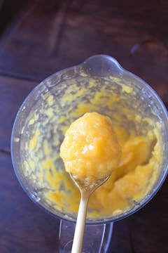 smooth mango jam in spoon over food processor