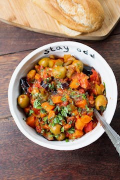 carrot caponata in a white bowl with crusty bread served on the side