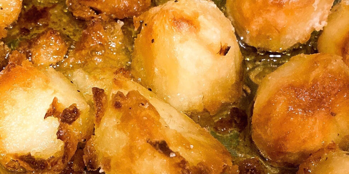 Golden brown roasted potatoes in a tray