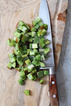 diced kiwi with skin on a chopping board
