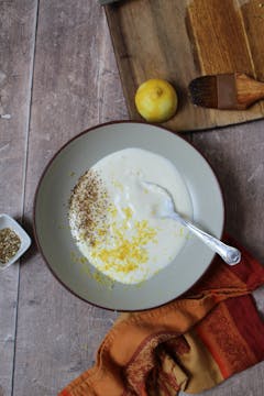 bowl of yogurt with half of the zaatar, chopped garlic, lemon zest and juice