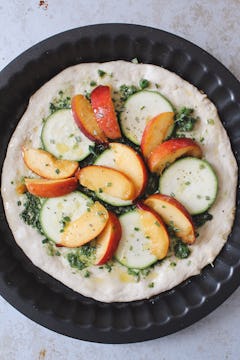 The peaches and nectarines added to the pizza, which is already topped with pesto and courgette. 