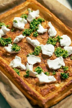 Cream cheese and pesto splodged around a prebaked tart base.
