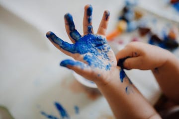 A child's hand covered in blue paint