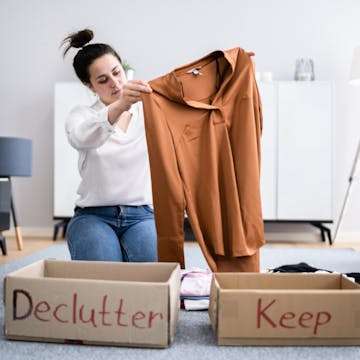 a woman organising a declutter pile and a keep pile