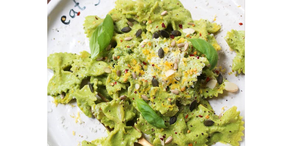 broccoli pesto pasta topped with cheese and basil leaves