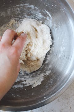 A hand kneading the pizza dough.