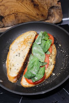 bread slices with tomato and basil cooking in frying pan 