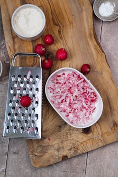 Grated radishes in bowl, grater box on table