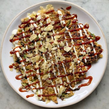 savoy cabbage okonomiyaki criss-cross with drizzles of sauce and mayonnaise