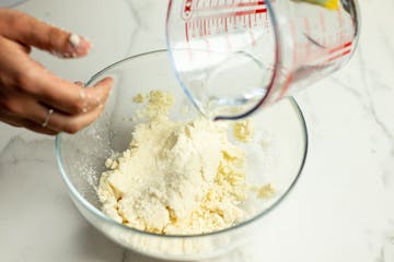 dry ingredients for the tacos in bowl and water getting poured over to make a dough