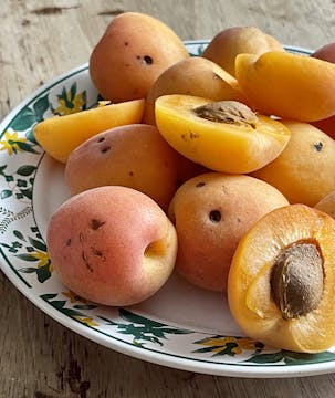 plate with whole and half cut apricots.