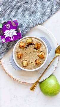 spiced fruity baked oats in a white bowl with a gold spoon