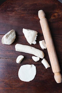 The different shapes that the potsticker dough goes into, from a log to a piece, to a ball, to a ball flattened into a wrapper. 
