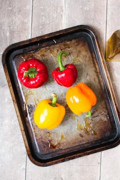 4 bell peppers (2 red 2 yellow) on a roasting tray coated in olive oil. 