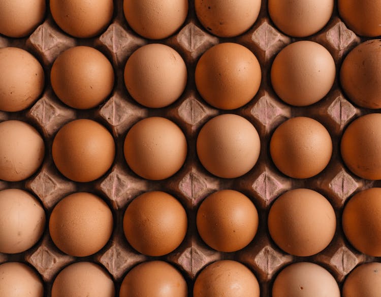 A closeup shot of around 30 eggs all in a carton.