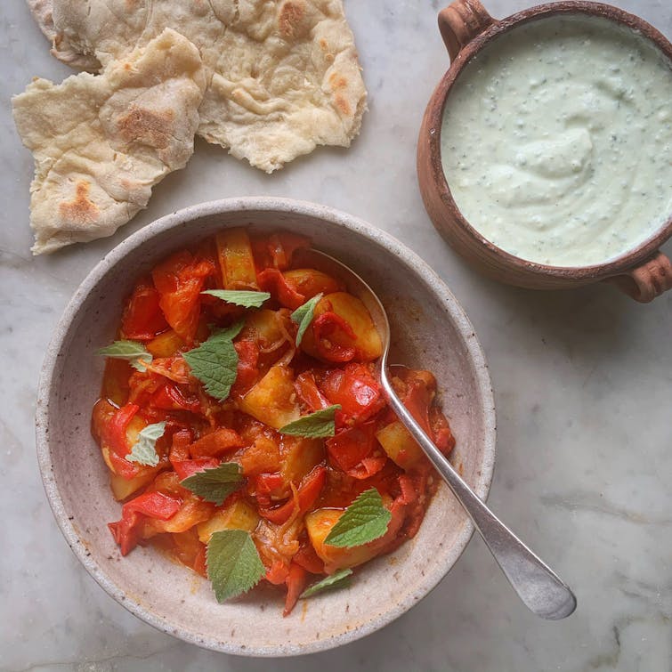 served smoky red pepper, tomato and potato stew in a bowl served with pitta bread and whipped feta