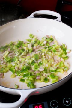 Onion and celery being fried in a pan