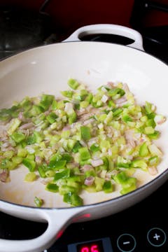 Onion and celery being fried in a pan