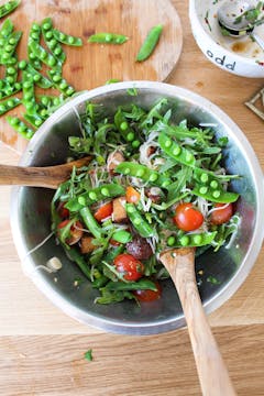 salad being tossed in a bowl