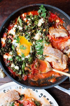 Cooked shakshuka in pan with bread and oddbox plate on the side 