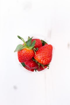 A small bowl of strawberries on a white countertop.