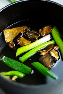 Dried mushrooms bowling with spring onion, stock, and garlic.
