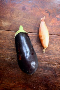 an aubergine and a shallot on a wooden bench